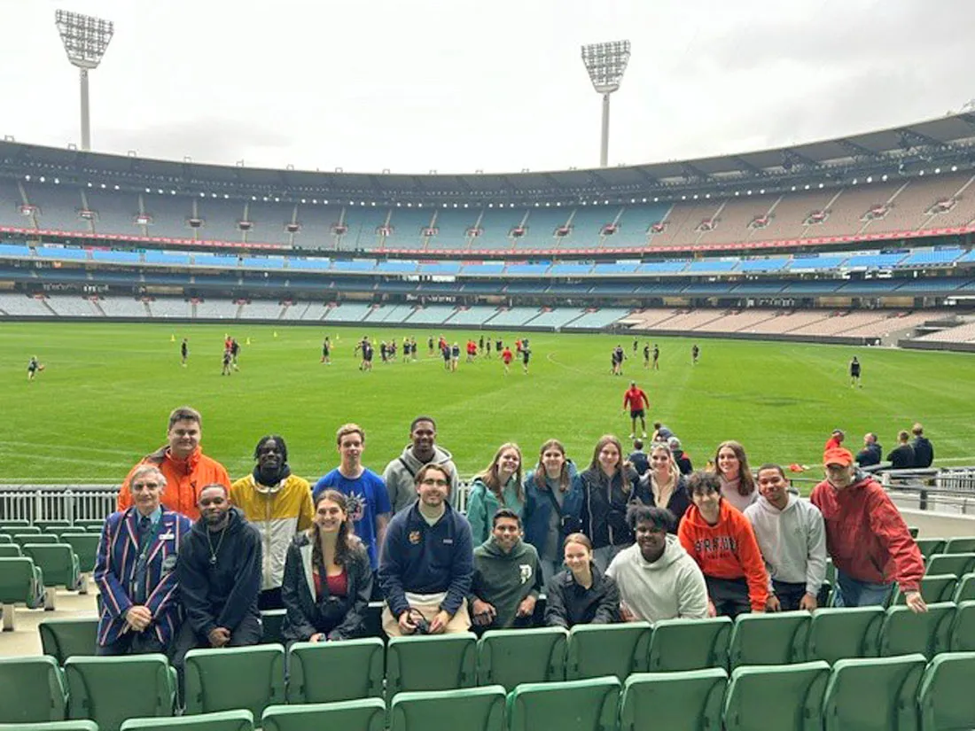 SU students sitting on the field of a rugby game in Australia