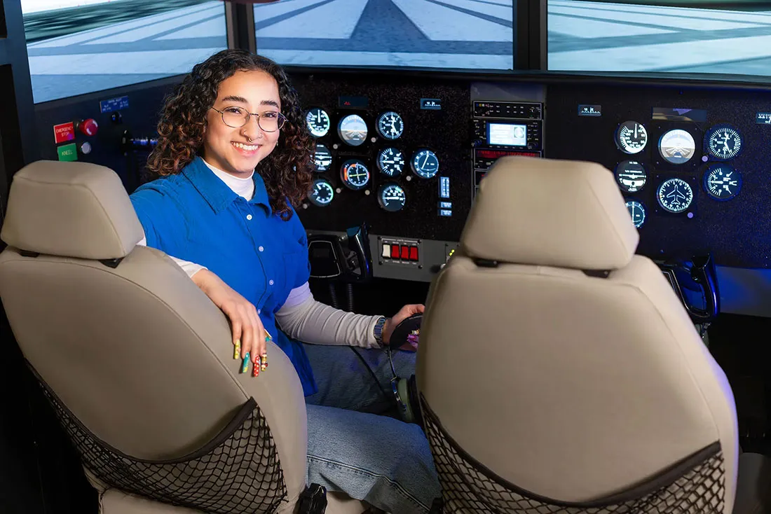 female student sitting in cockpit of a plane