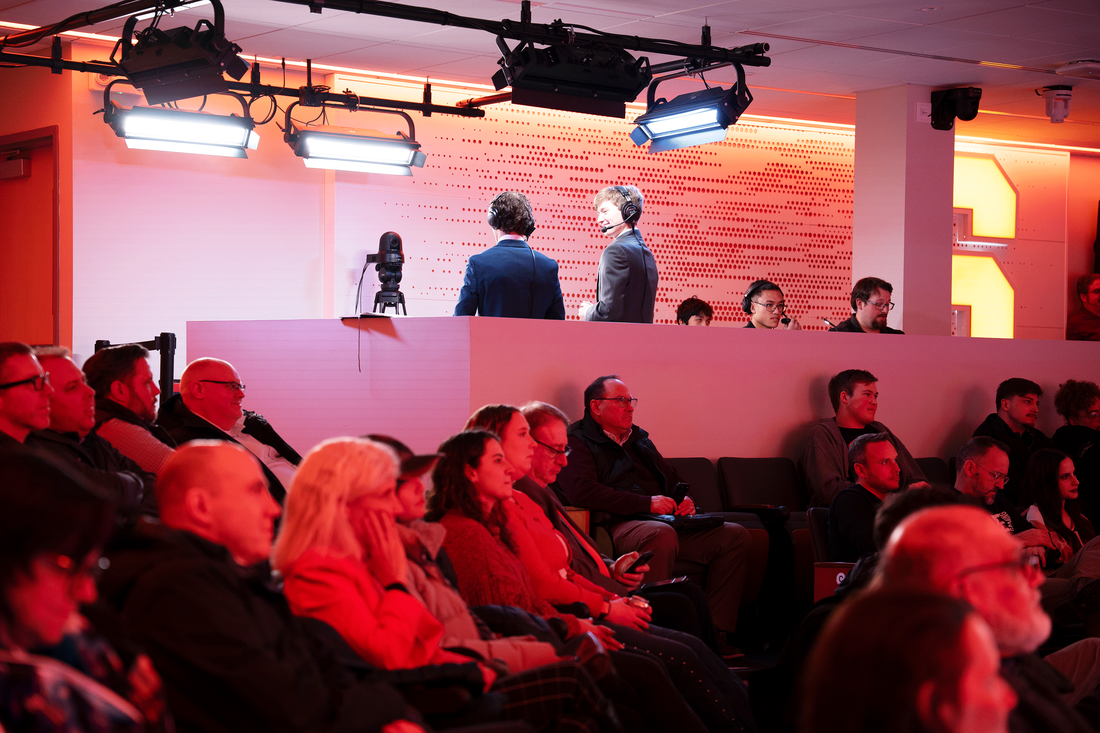 A diverse crowd of people intently watching a television show in a lively setting.