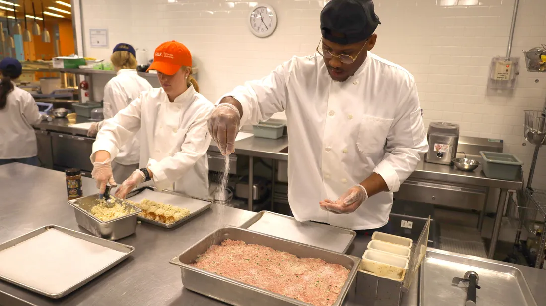 Derrell Smith prepares food with student Sophia Lee