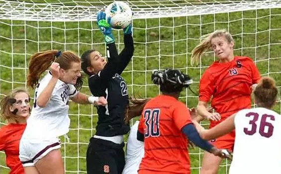 six female soccer players getting ball to the net