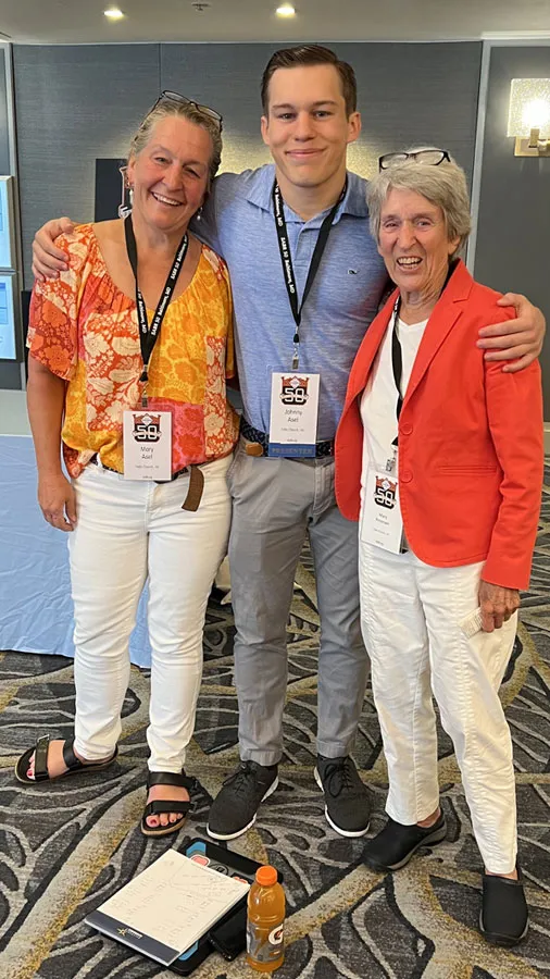 group of two women and one man standing together with arms around each other