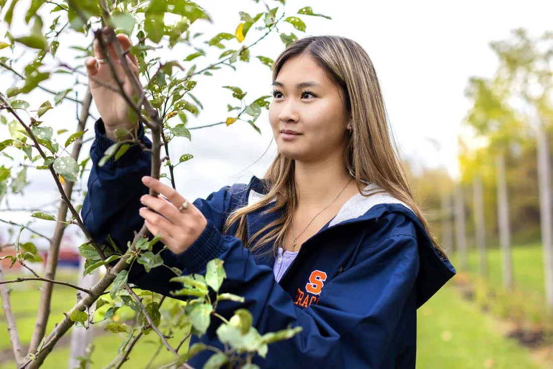 female student holding a branch of a rose bush