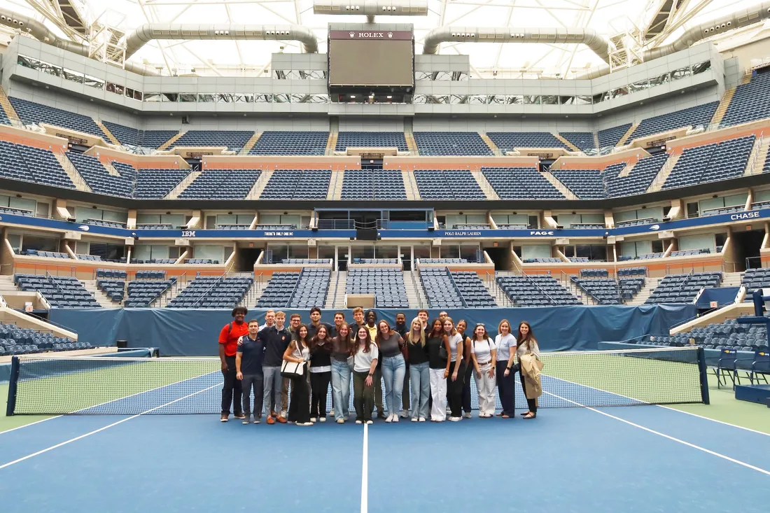 Students stand on the court at Arthur Ashe Stadium