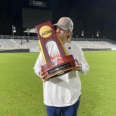 young man on athletic field holding a trophy