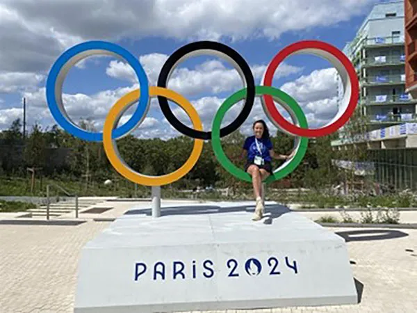 student standing in front of olympic symbol in Paris