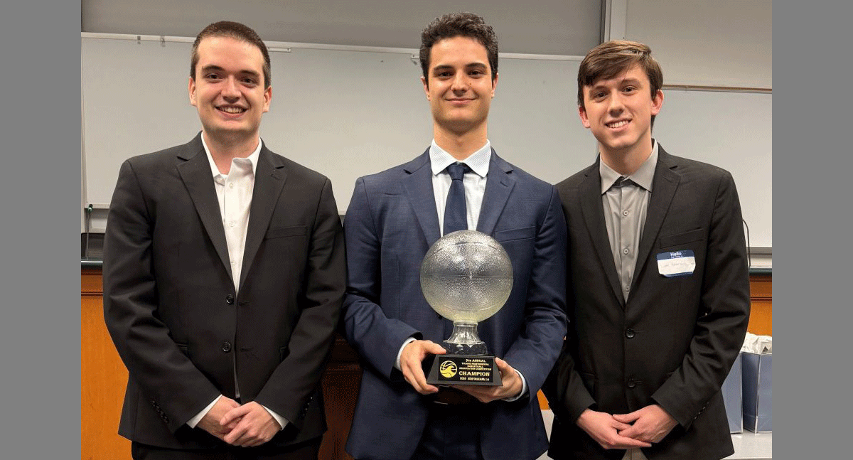 Three male students standing together while middle person holds award
