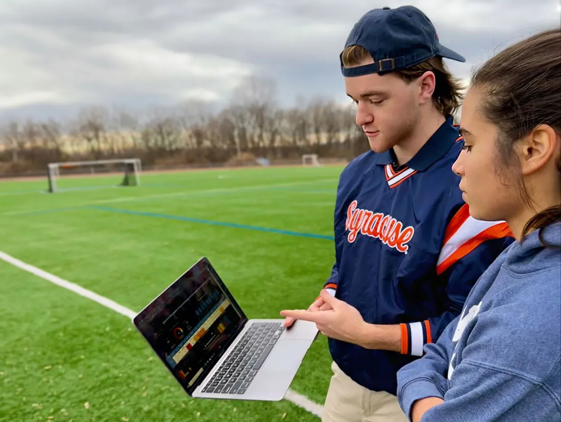 Sport Analytics student analyzing data on a laptop on a soccer field