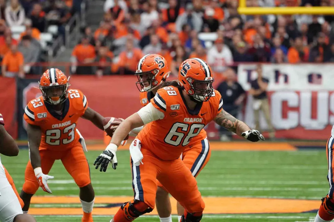 football players in orange and blue playing on athletic field