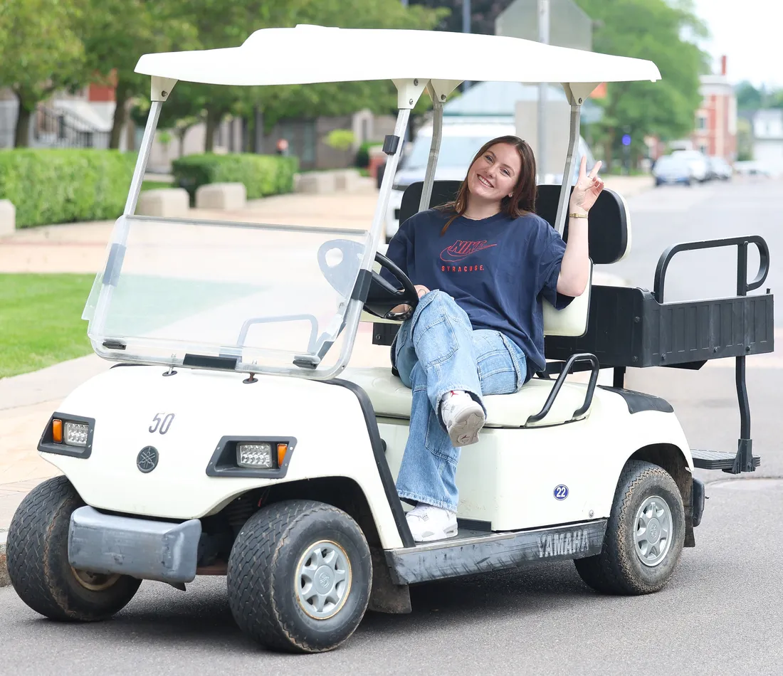 Justy Carruthers smile and waving while driving a golf cart