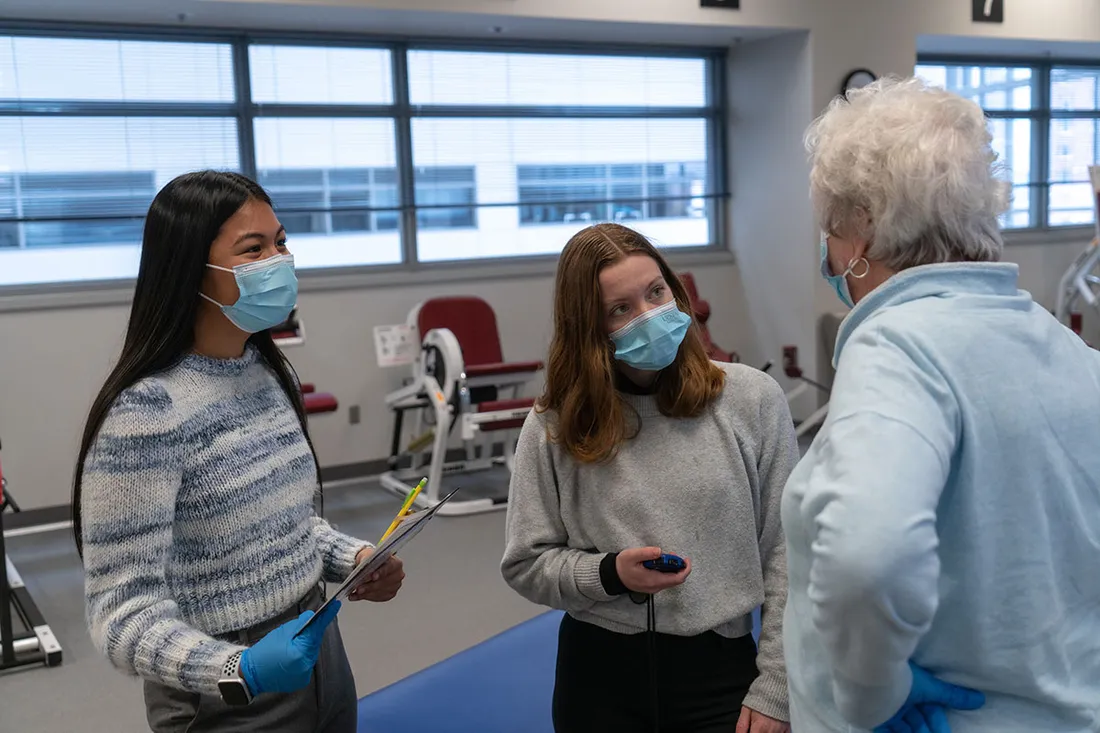 two student interns talking with a woman at the Institute for Human Performance at Upstate Medical University