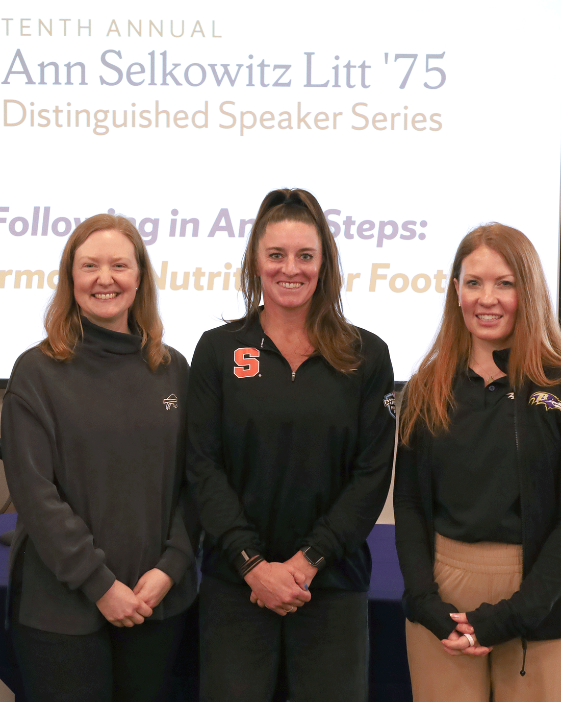 3 young women standing together in front of screen promoting Ann Litt lecture series