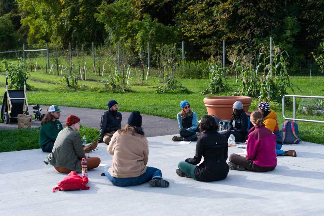 group sitting on concrete slab looking at vegetable garden