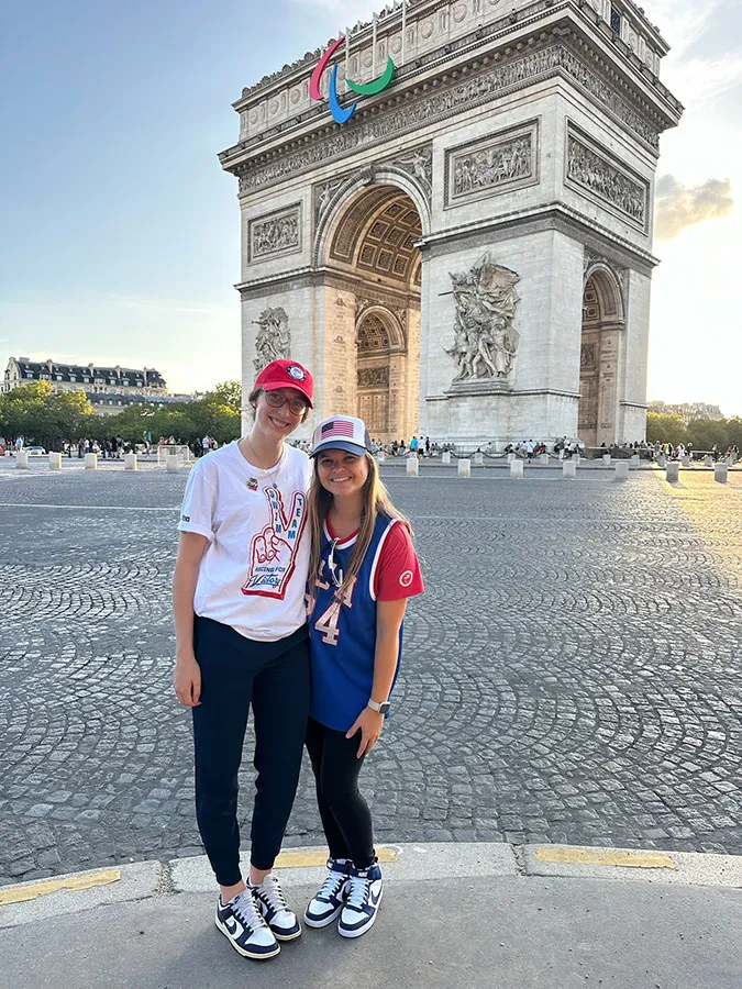 two young women standing in front of the Arc de Triomphe