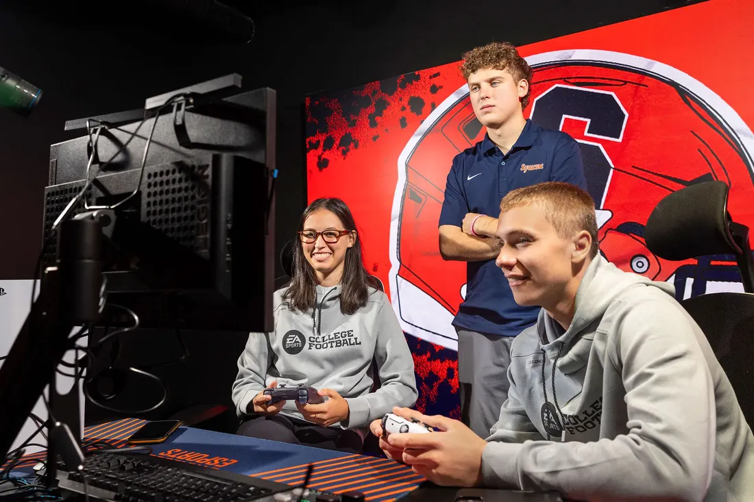 Junior Jack McAllister standing behind two students gaming