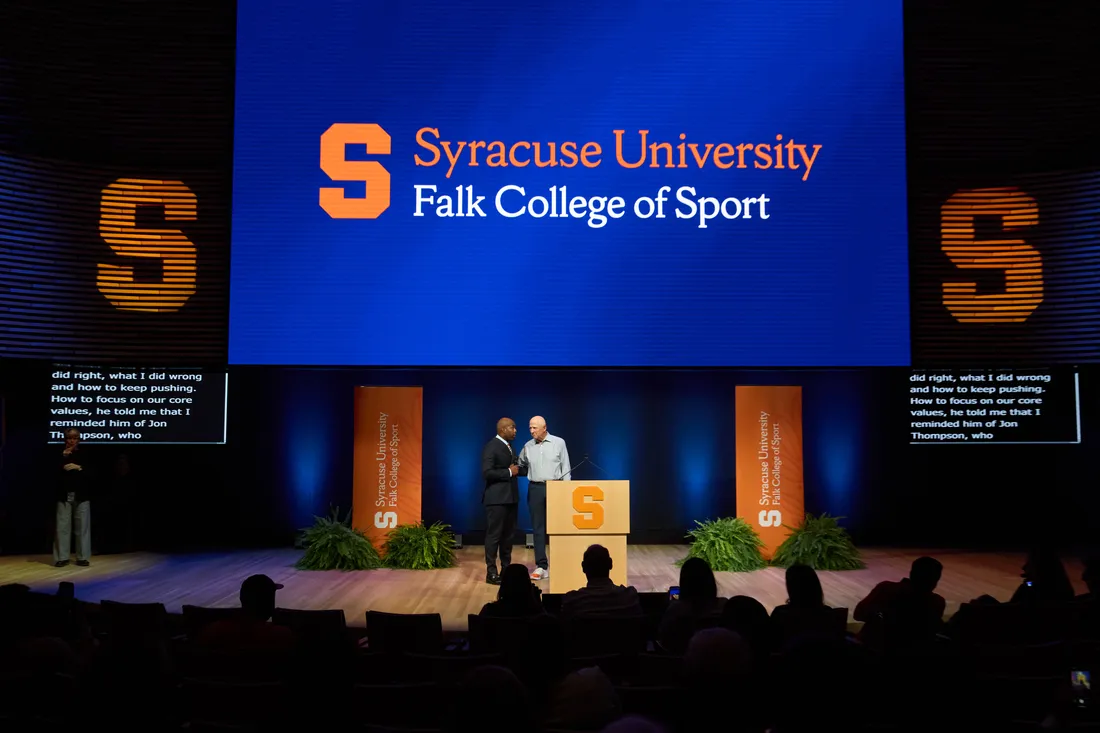 Two men shake hands on a stage