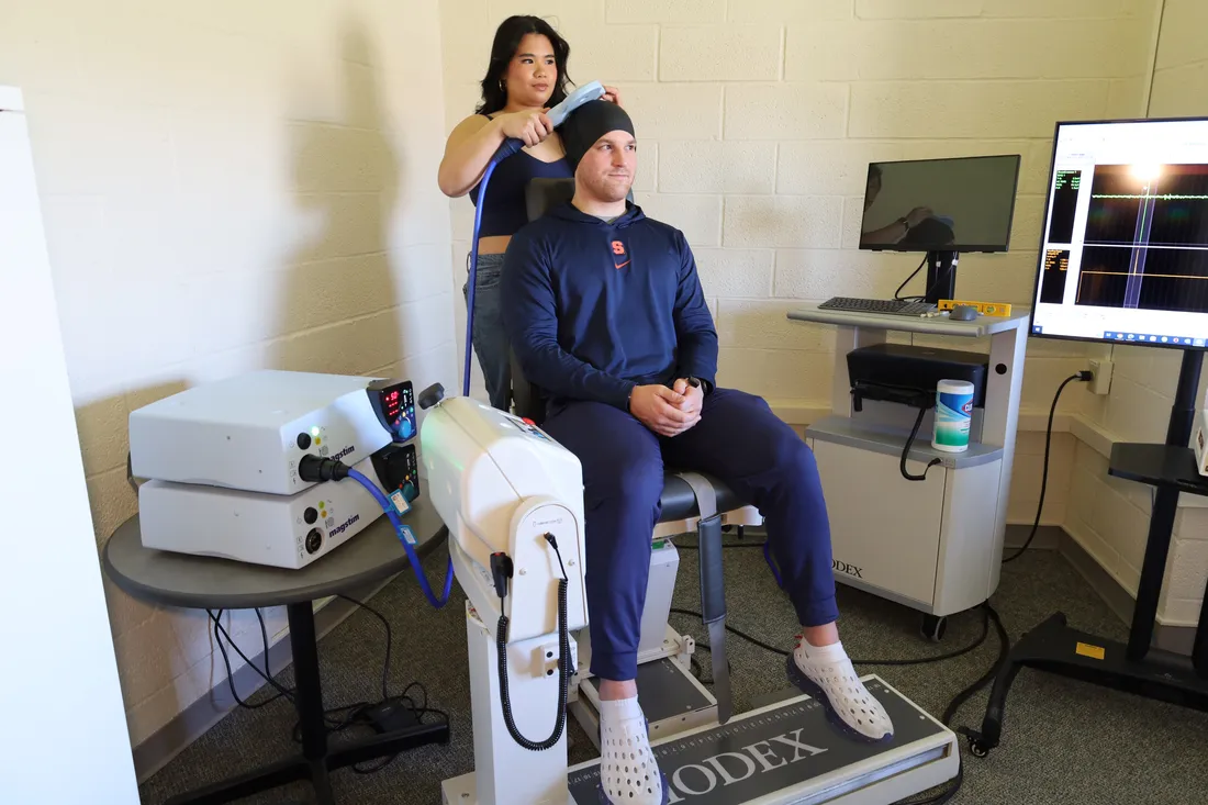 A student examines an athlete with brain scanning equipment