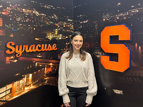 female student standing in front of SU logo