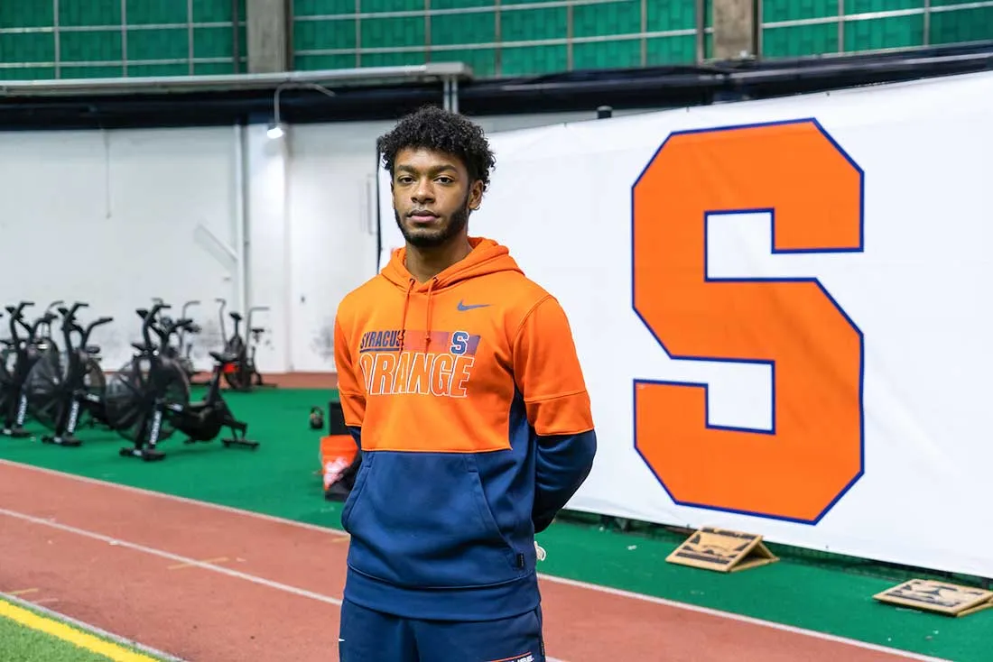 student in blue and orange hoodie standing on SU track