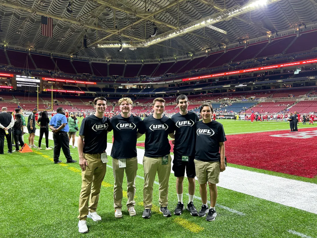 5 sport analytics students standing in a row on athletic field