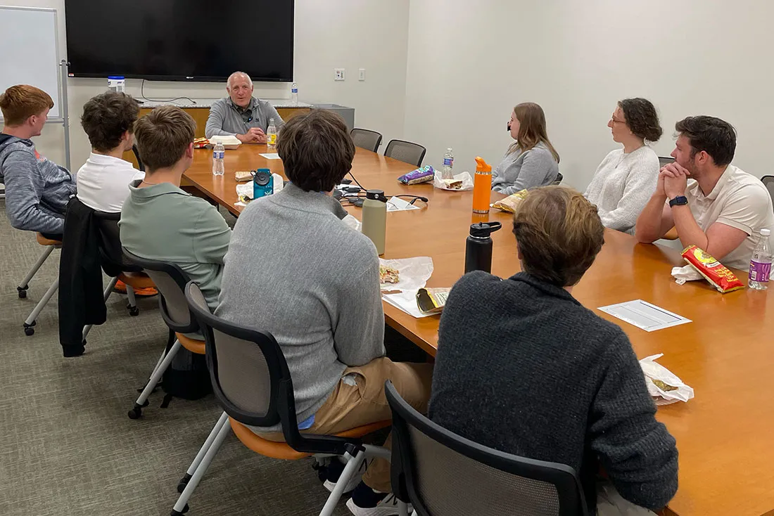 students sitting around a table talking with Brandon Steiner