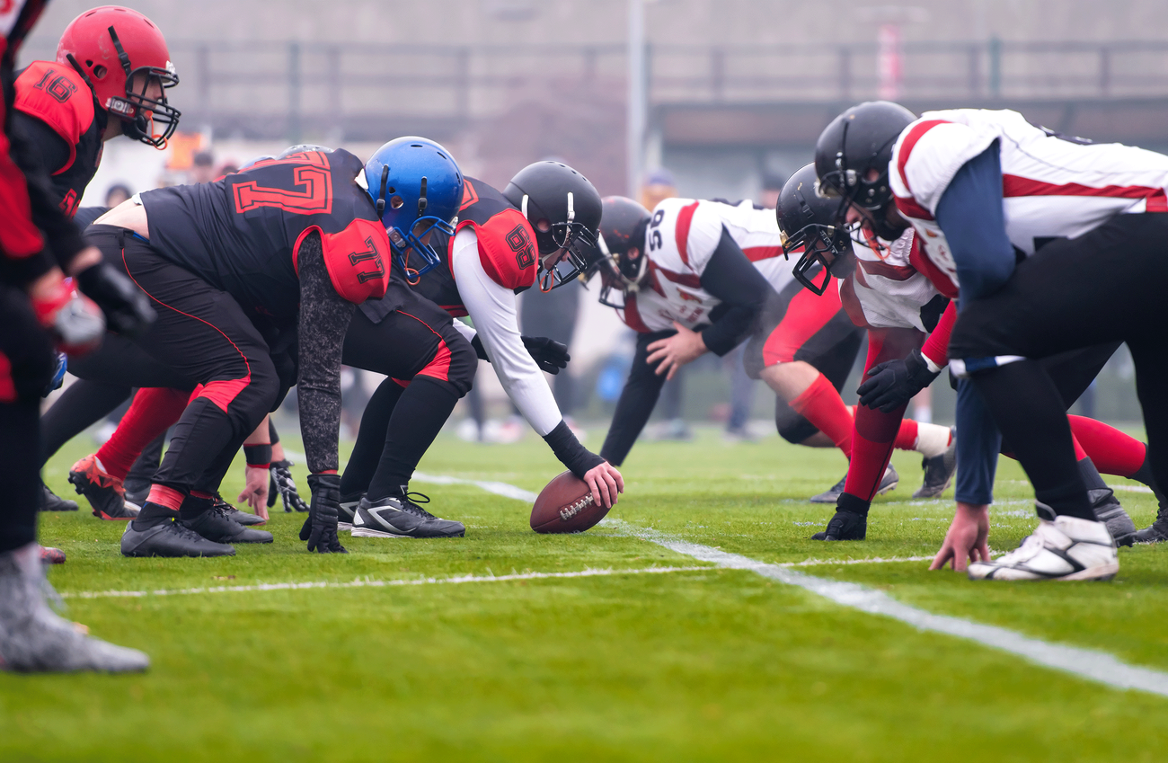 Two football teams on athletic field, ready to hike the ball