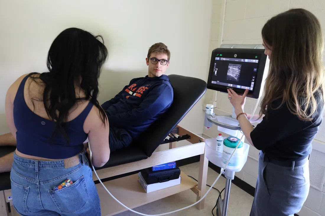 Students and professor monitor a student athlete