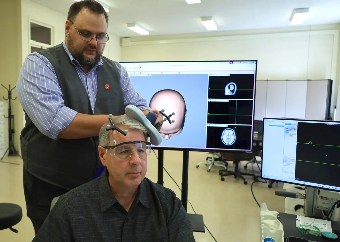 Falk College faculty member performing a brain test on a test subject.