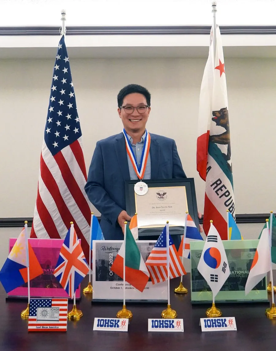 assistant professor standing at a podium with flags displayed and medallion