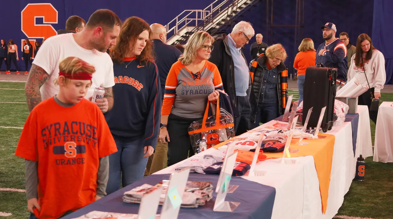 people looking at items displayed on a table for the SPM charity auction