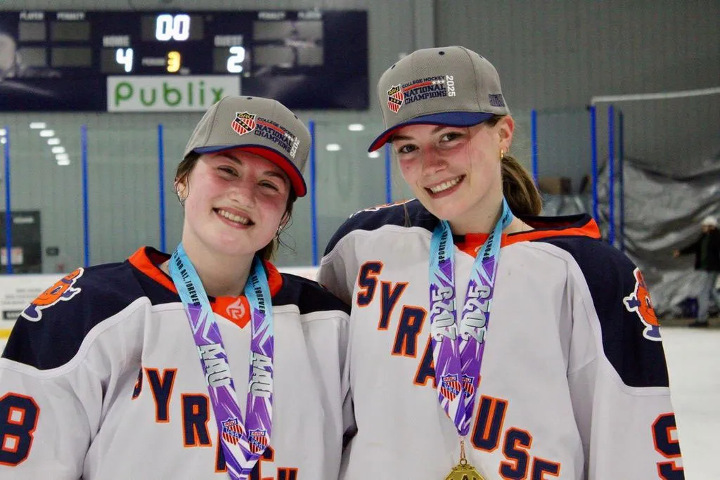 two SU female hockey players stand together