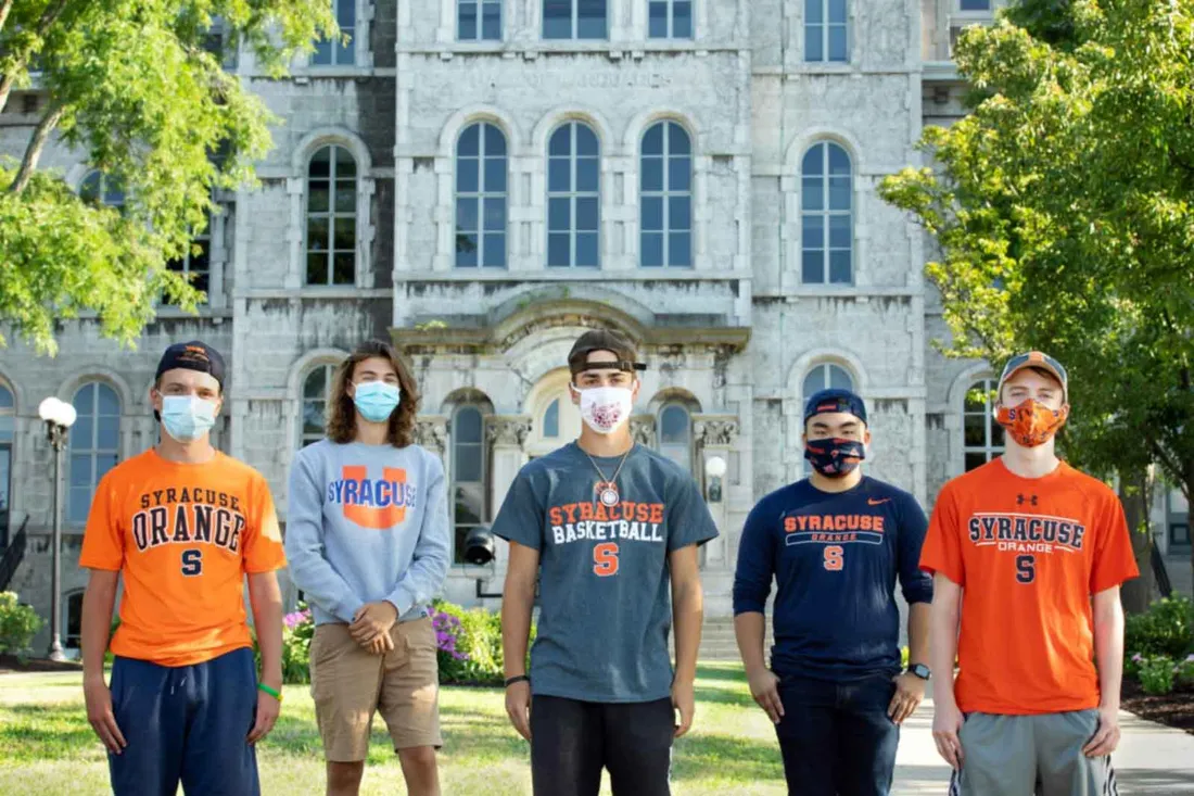 Six Corcoran high school graduates stand outside the hall of languages. Students are wearing masks.