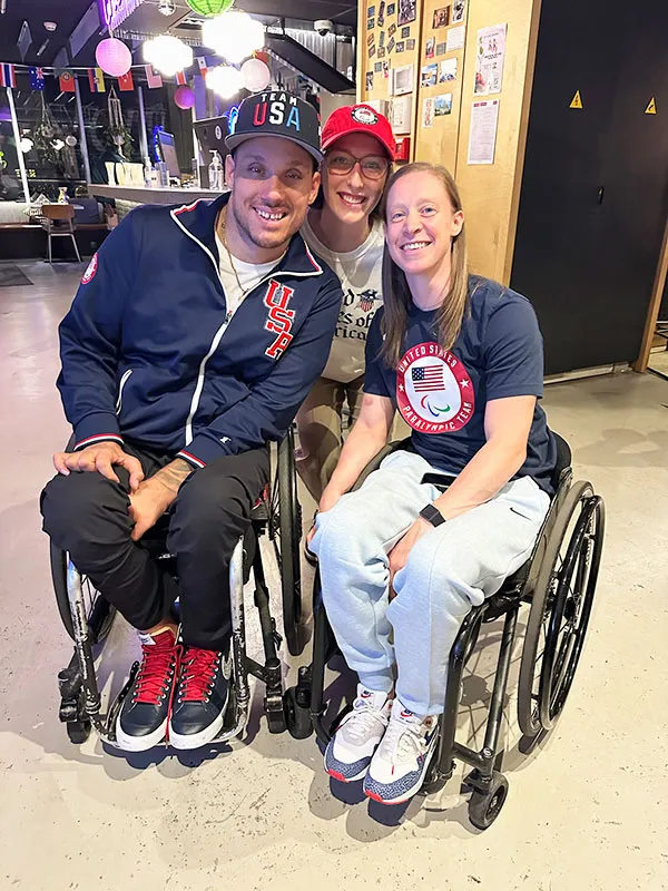 student squatting behind to paralympic participants in wheelchairs