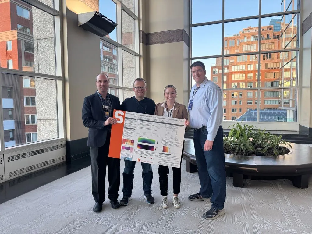 Four members of research team stand together holding poster presentation