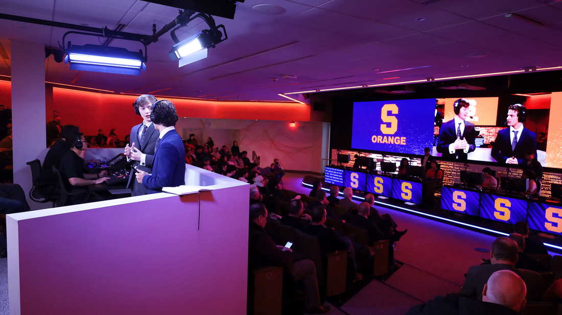 A large room filled with people seated around a long table, engaged in discussion or collaboration.
