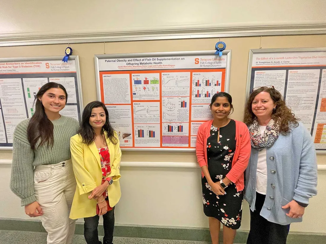 students presenting poster with faculty member