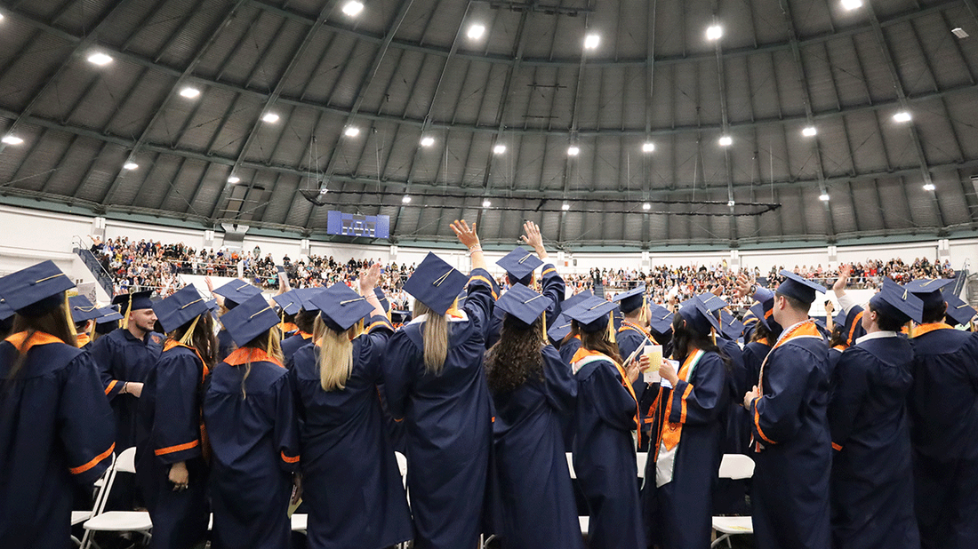 from behind students standing at the end of convocation ceremey