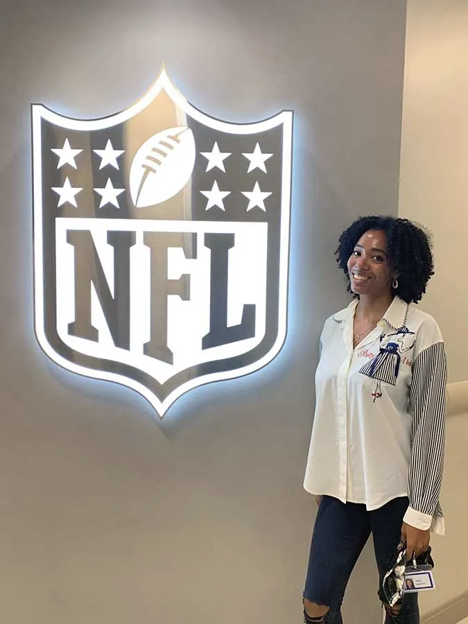 young women standing next to NFL logo on the wall