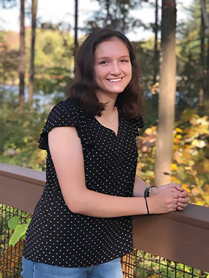 portrait of young woman with long dark hair outside with leaves of yellow and fall colors
