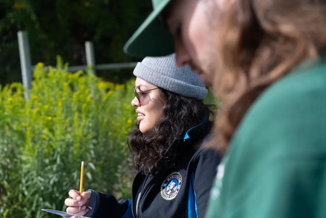two women outside surrounded by greenery