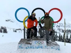 students standing in front of the olympic rings during winter olympics