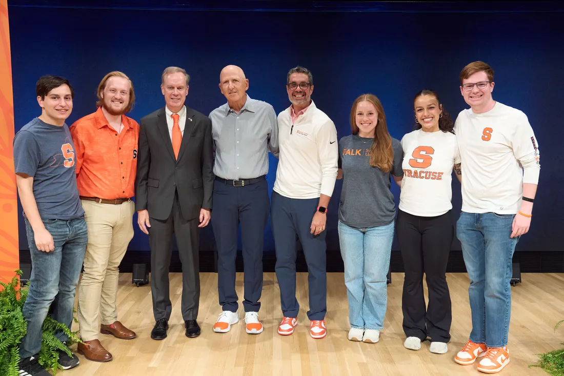 A group of students are posed with David Falk and the Chancellor of Syracuse University