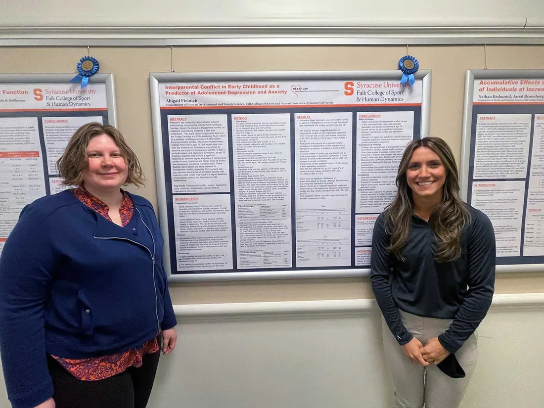professor and student stand next to poster that was presented