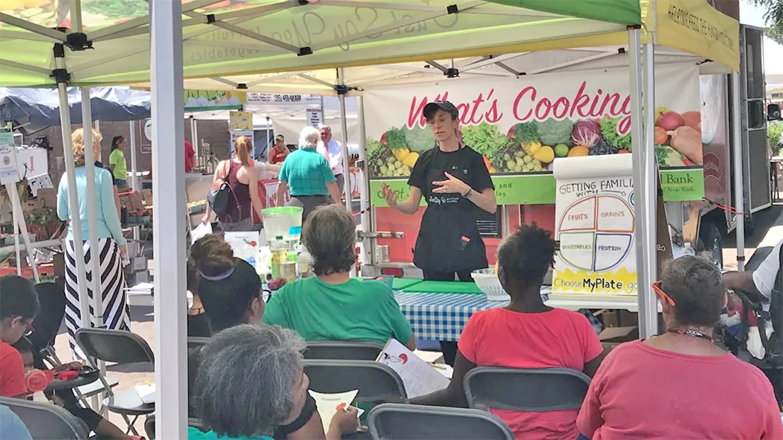 women presenting to attendees at farmer's market