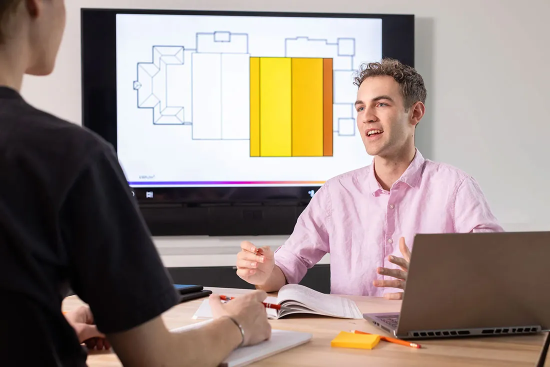 male student sitting at table discussing climate crisis with another person