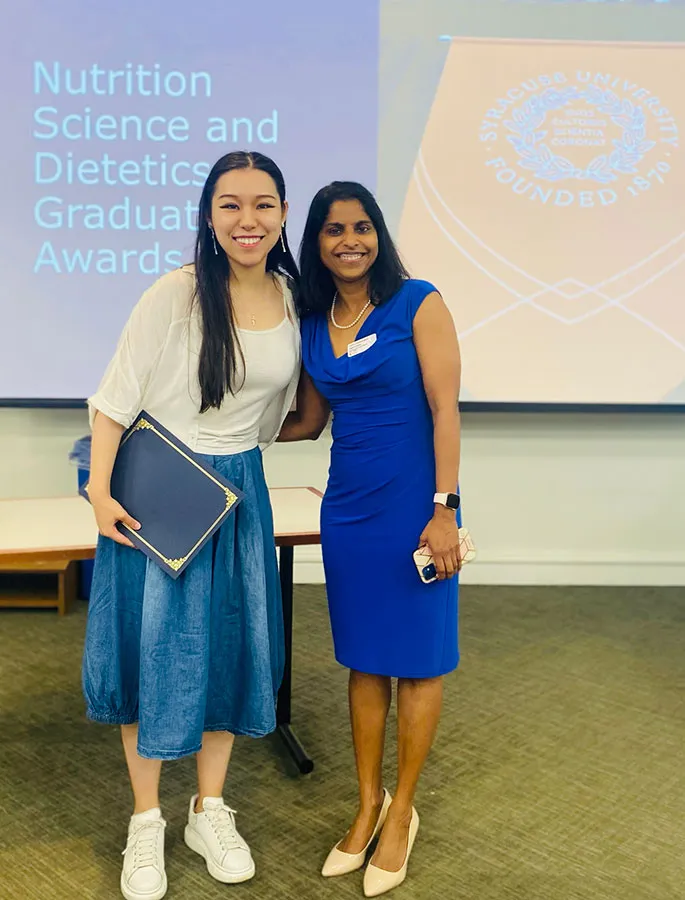 female student standing with her female professor, both smiling