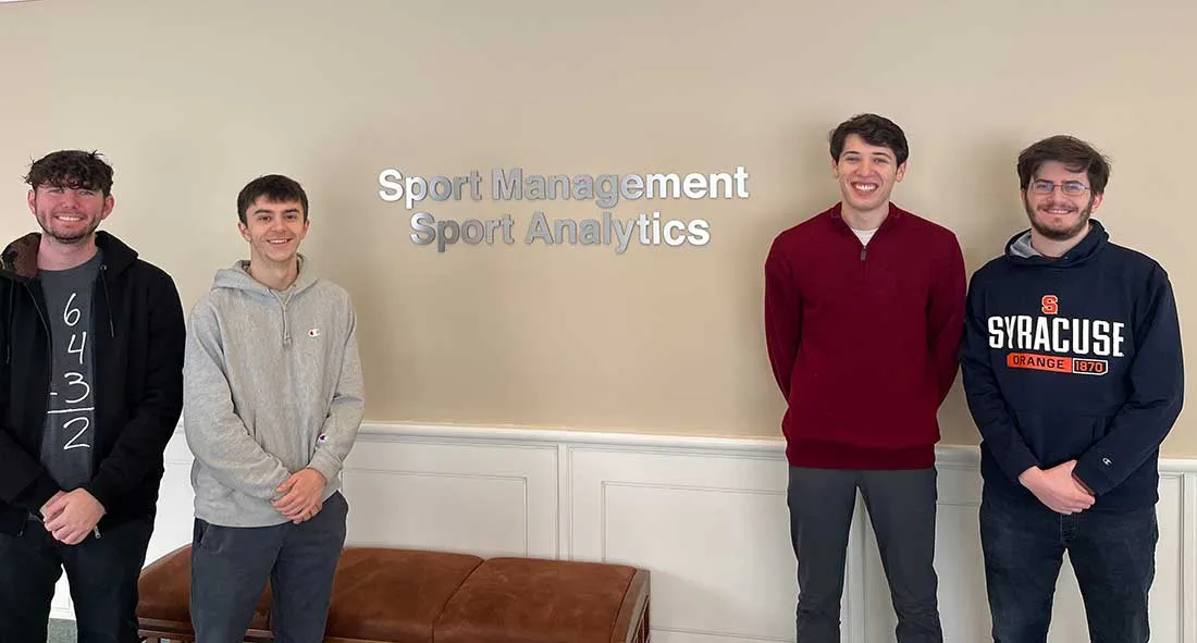four male student standing in front of sport management sign outside its office