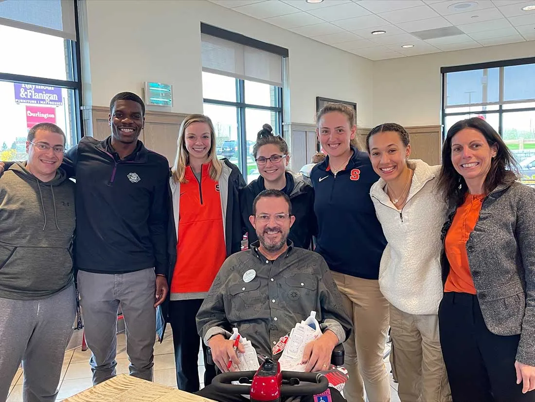 front and center male in wheelchair with a group of seven people standing behind him