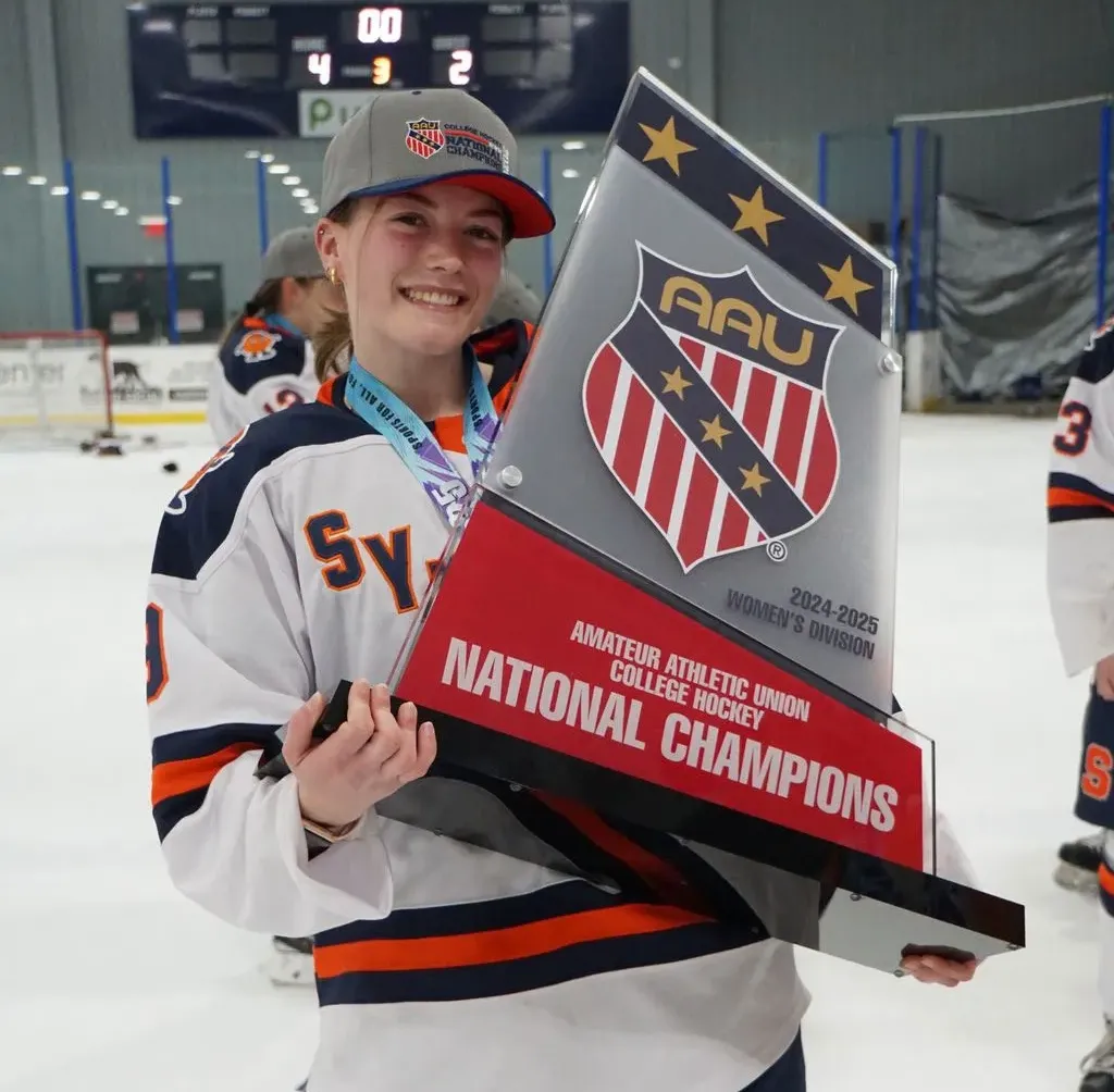 a hockey women athlete holds a large trophy