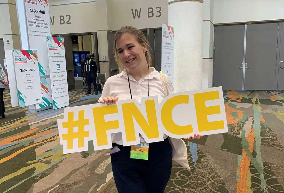 student at conference holding up #FNCE sign